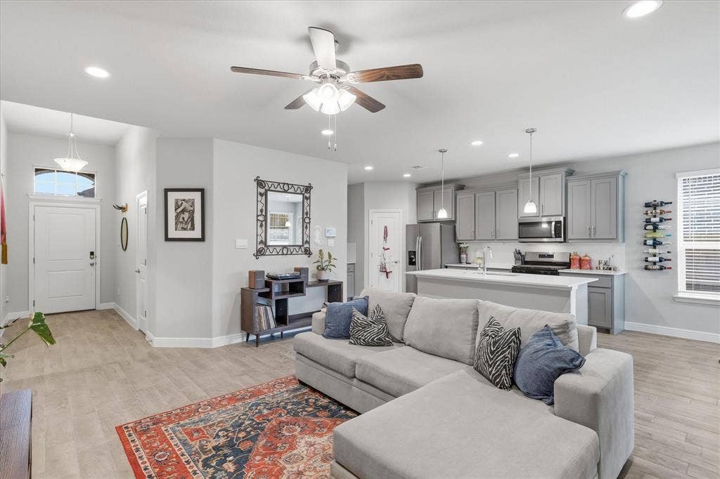 Open-concept living area with wood-finish flooring, recessed lighting, and a ceiling fan