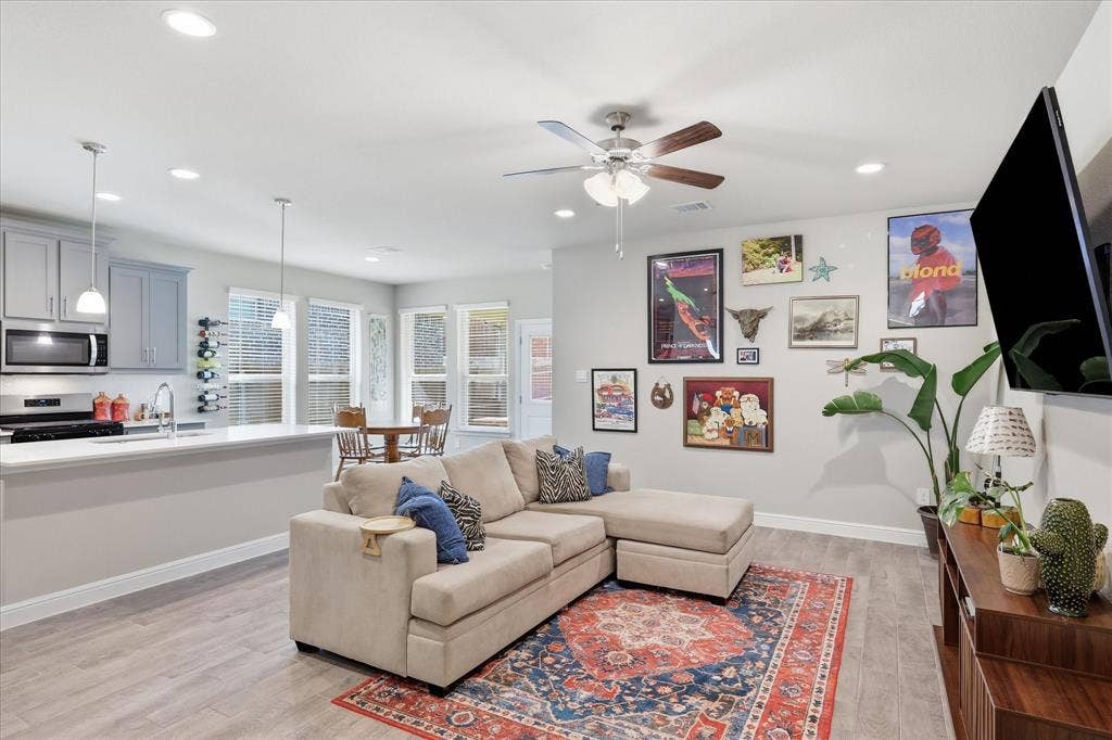 Open-concept living space with wood-finish flooring, recessed lighting, and a ceiling fan