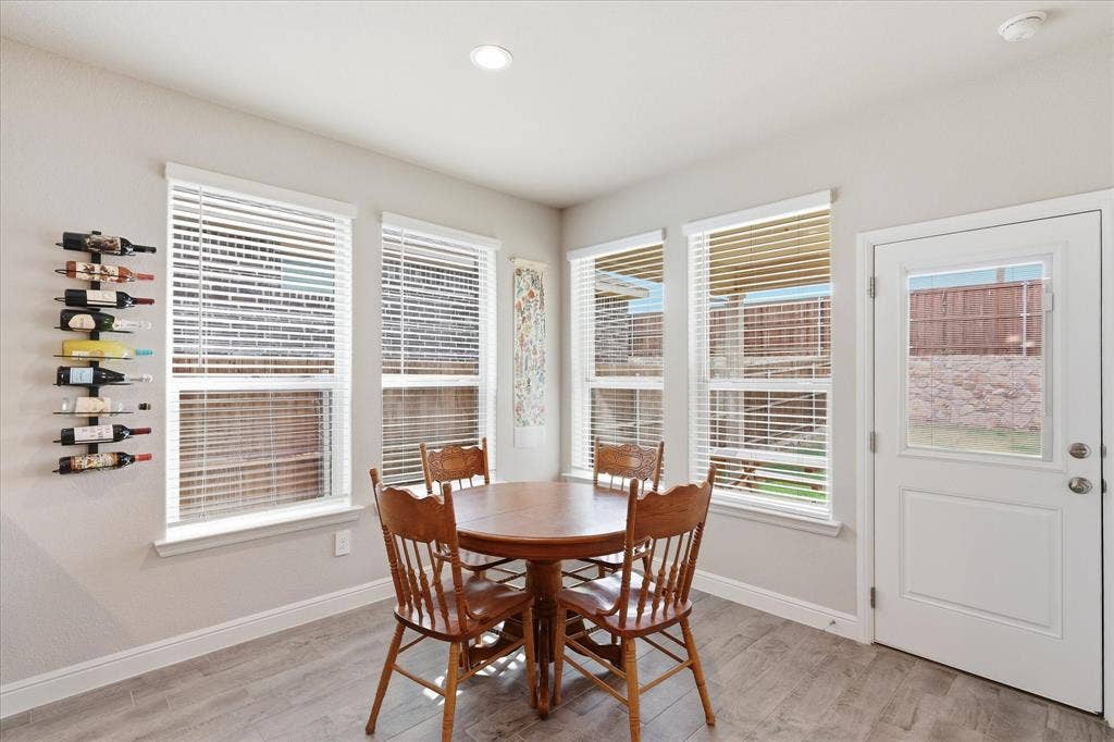 Recessed lighting, wood-finish flooring, multiple windows, built-in wine rack, and a glass-paneled door
