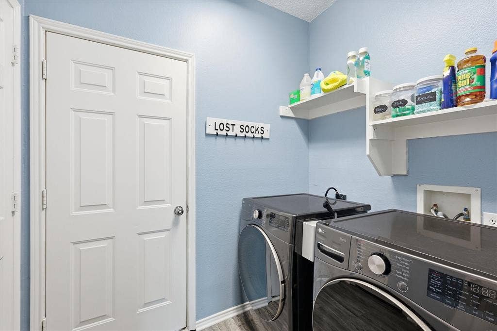 2112 Loon Lake Road, Denton, TX 76210 Dedicated laundry space featuring a side-by-side washer and dryer, built-in wall shelving, and wood-finish flooring