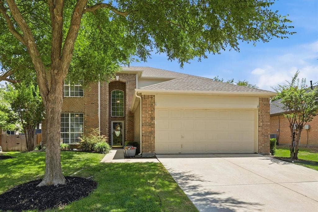 2112 Loon Lake Road, Denton, TX 76210 Brick and siding exterior with a two-car garage, concrete driveway, and front entryway with an arched window