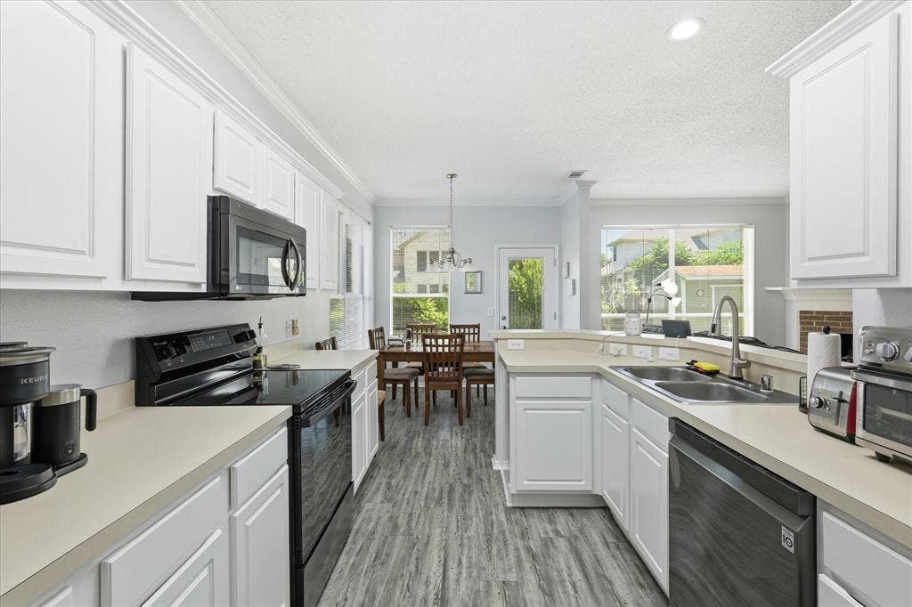 2112 Loon Lake Road, Denton, TX 76210 White cabinetry, light-toned countertops, black built-in microwave, black electric range, and wood-finish flooring