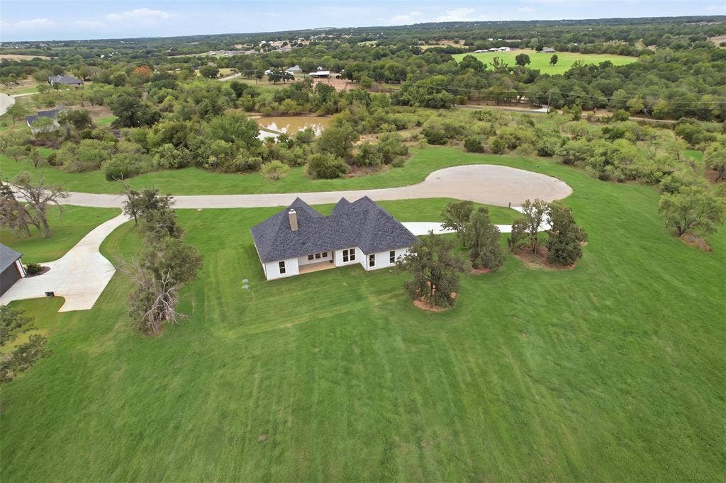 124 Norene Lane, Weatherford, TX 76088 Expansive green space surrounding the residence, featuring a white exterior and dark shingle roofing
