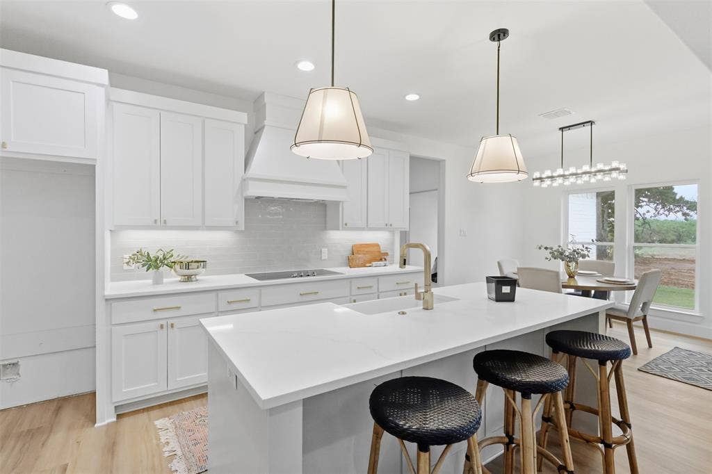 124 Norene Lane, Weatherford, TX 76088 Open-concept kitchen with white shaker cabinetry, gold-finish hardware, quartz countertops, and wood-finish flooring