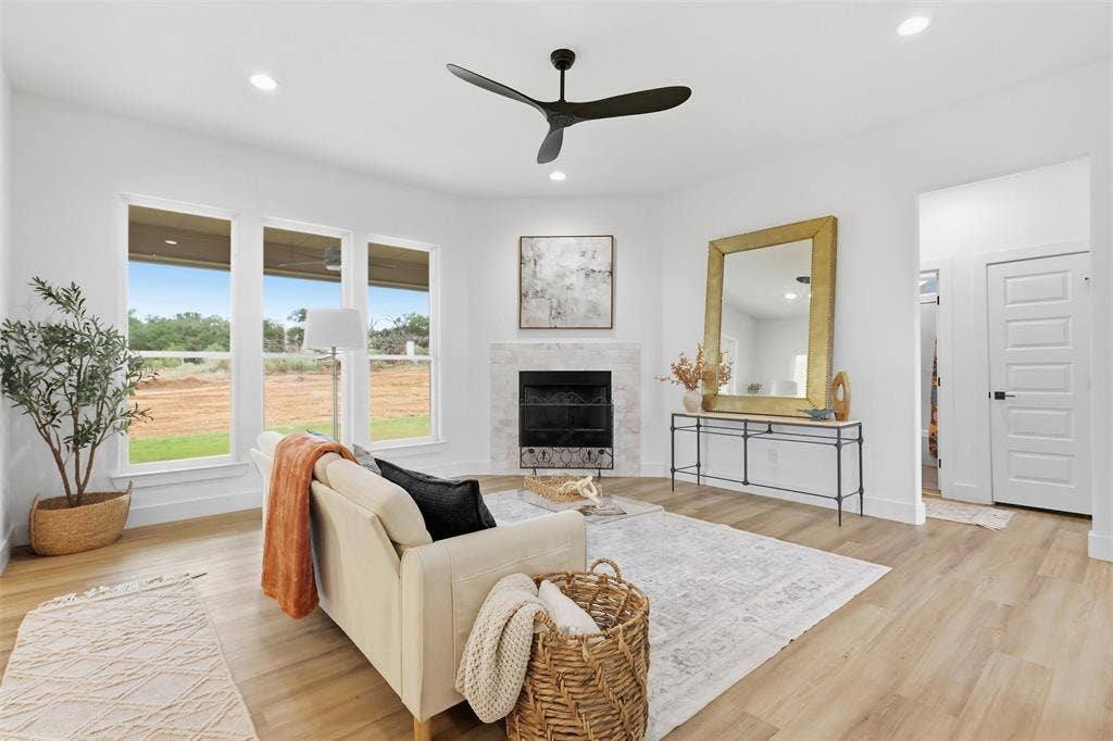 124 Norene Lane, Weatherford, TX 76088 Recessed lighting, a modern ceiling fan, wood-finish flooring, a fireplace with a stone surround, and multiple windows
