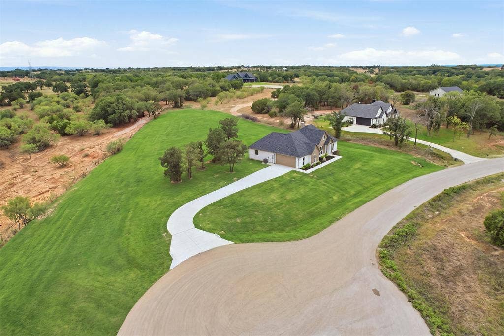 124 Norene Lane, Weatherford, TX 76088 Expansive green lawn, long concrete driveway, single-story residence, asphalt road, surrounding natural landscaping