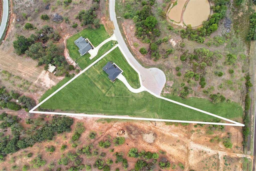124 Norene Lane, Weatherford, TX 76088 Expansive lot featuring a manicured lawn, established landscaping, and a paved driveway