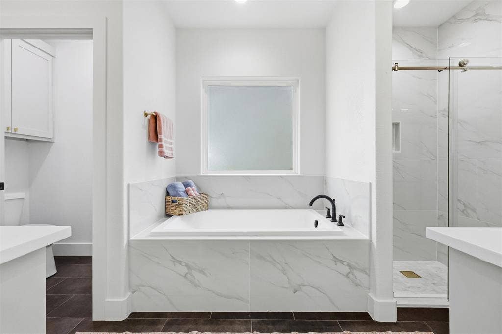 124 Norene Lane, Weatherford, TX 76088 Soaking tub with black fixtures, frosted window, white marble-look surround, and walk-in shower with glass enclosure
