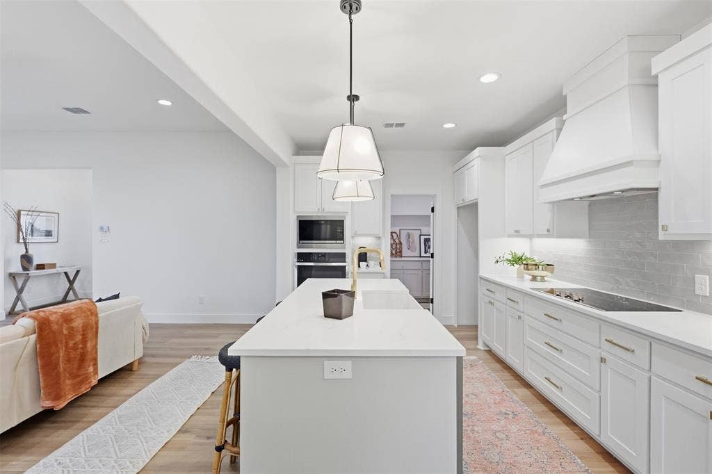 124 Norene Lane, Weatherford, TX 76088 Kitchen featuring an expansive center island, white shaker cabinetry, white countertops, built-in stainless steel appliances, and wood-finish flooring
