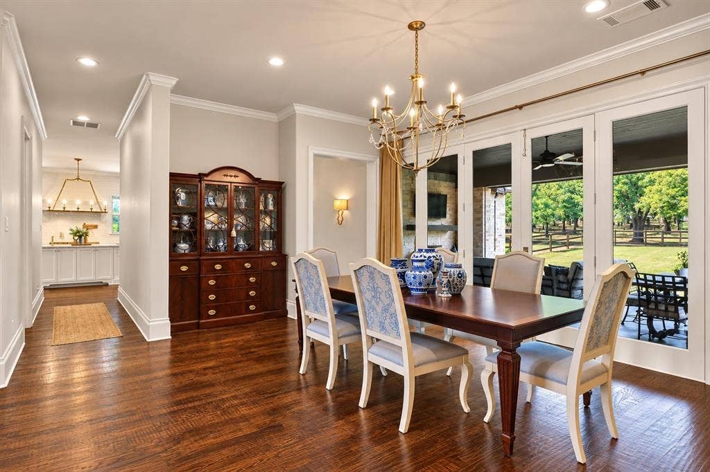 Hardwood flooring, crown molding, double French doors, recessed lighting, and an ornate brass chandelier