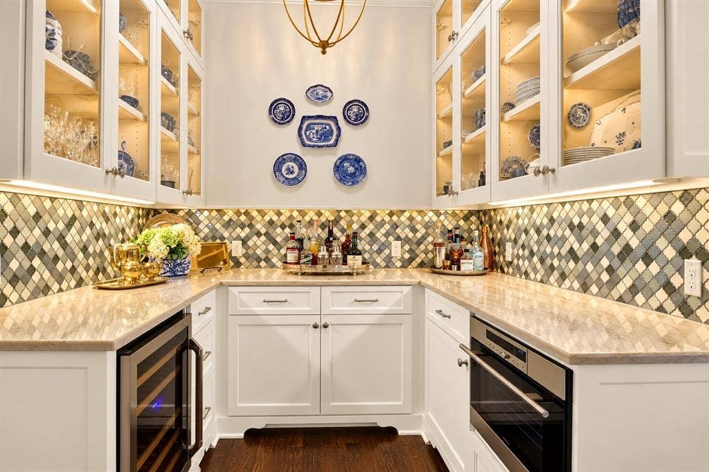 U-shaped counter featuring light-toned countertops, a mosaic tile backsplash, and white cabinetry with glass-front upper cabinets