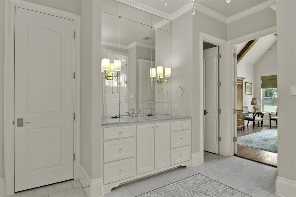White vanity with a marble countertop, dual undermount sinks, and paneled mirror