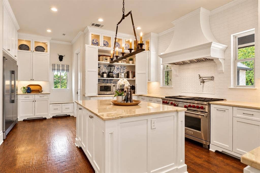 Bright kitchen featuring white cabinetry, a large central island with a light-toned countertop, and stainless steel appliances