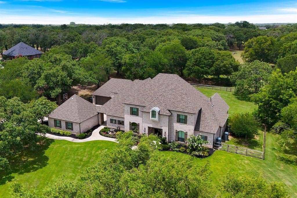 Expansive property with a brick exterior, multiple gables, a paved driveway, and mature landscaping