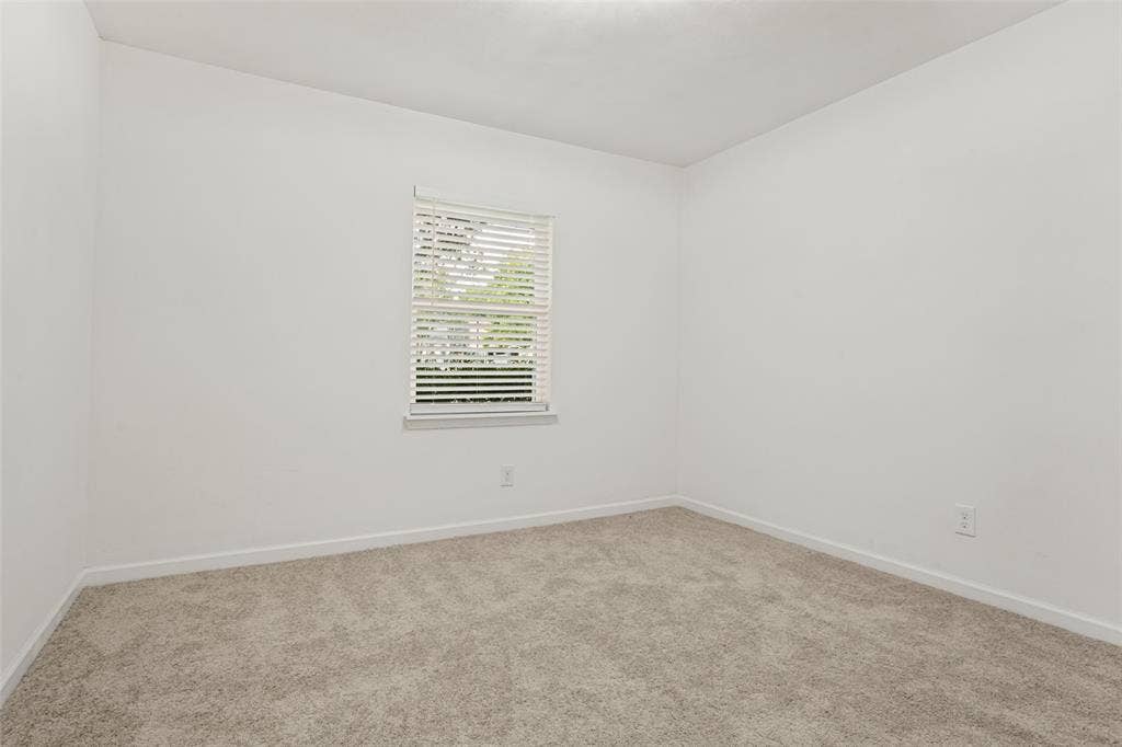 Window with blinds, light-toned carpeting, and neutral wall tones