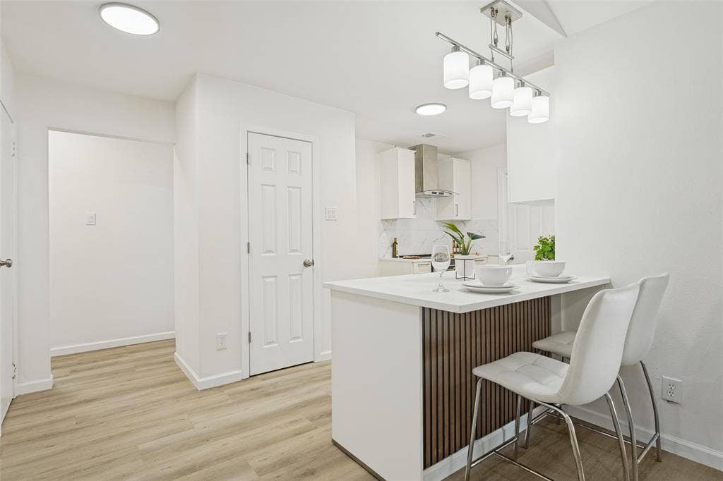 Kitchen featuring light-tone wood-finish flooring, recessed lighting, and a white countertop island with a wood-slat accent panel