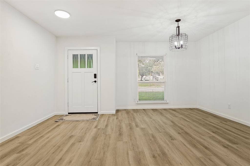 Wood-finish flooring, white walls, and a modern caged pendant light fixture