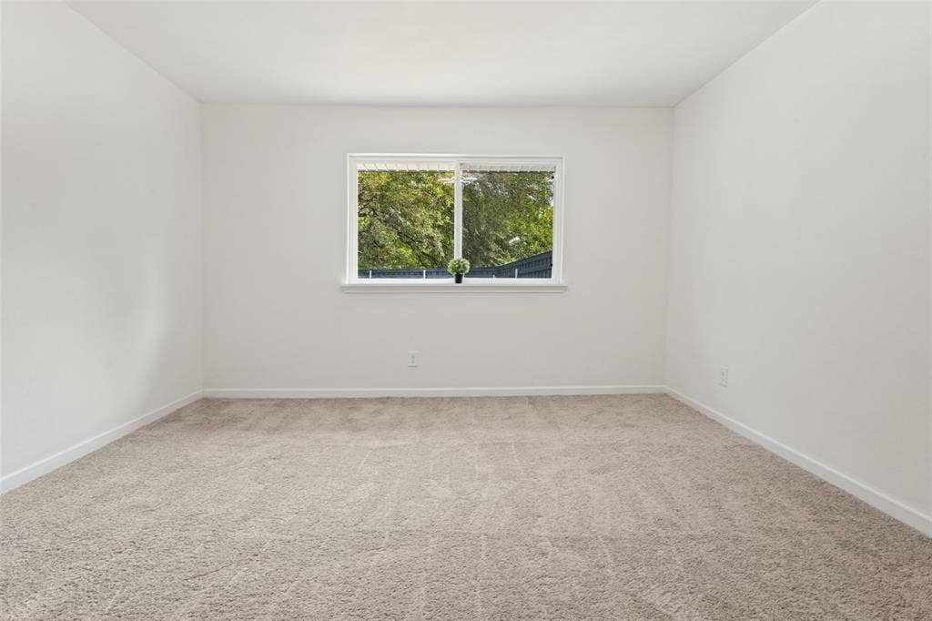 Neutral-toned carpeting, white walls, and a window with white trim