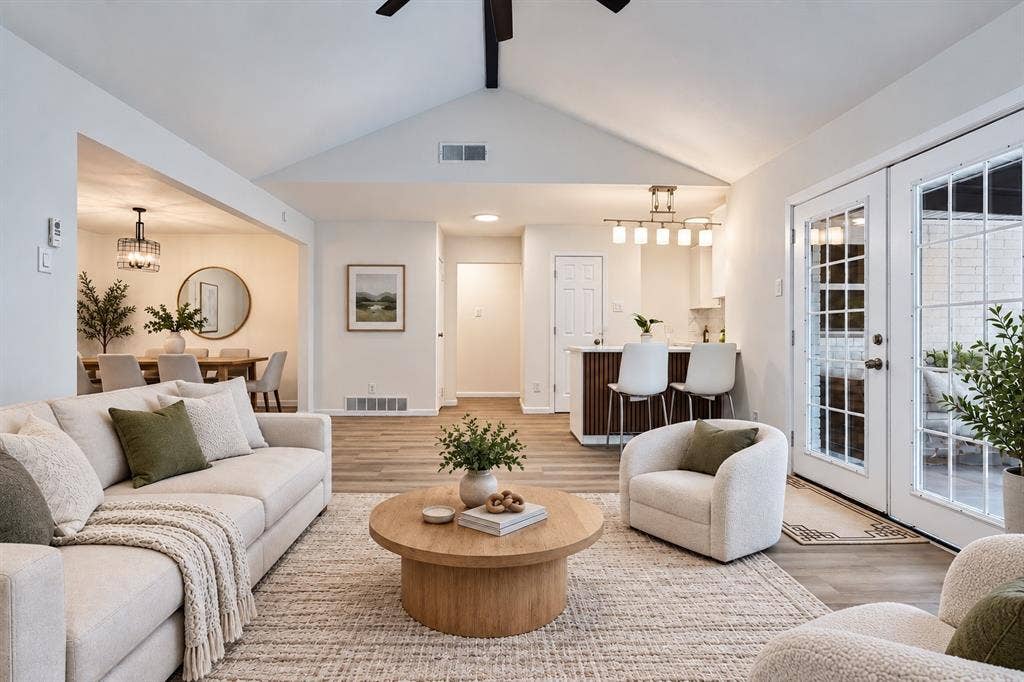Vaulted ceiling, wood-finish flooring, white double French doors with grid panes, built-in kitchen bar with seating, recessed lighting