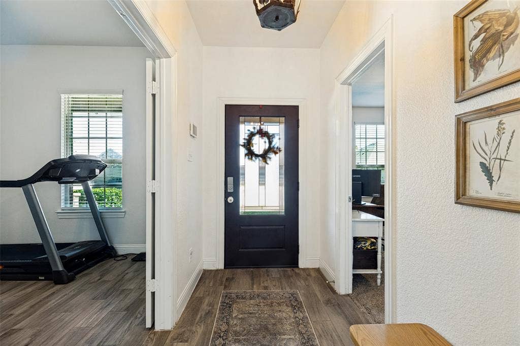Entryway featuring a dark wood-finish door with glass panels, wood-finish flooring, and white textured walls