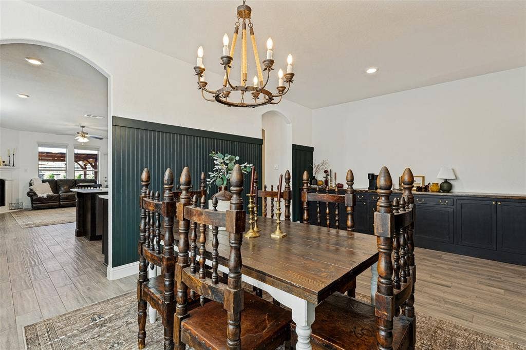 Dining area featuring a wood-finish flooring, an arched doorway, a decorative chandelier, and built-in cabinetry with a wood-finish countertop