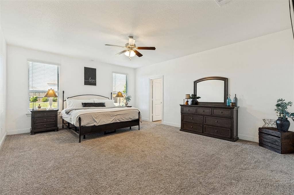 Spacious room featuring neutral carpeting, white walls, and multiple windows with blinds