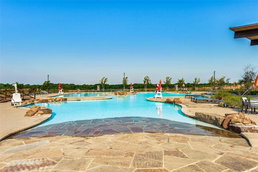 Expansive lagoon-style pool with natural stone decking, surrounding concrete patio, and integrated water features