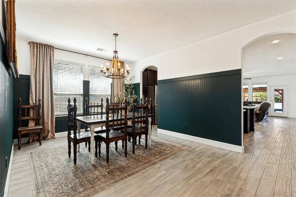 Light wood-finish flooring throughout, beadboard wainscoting, and a candelabra-style chandelier
