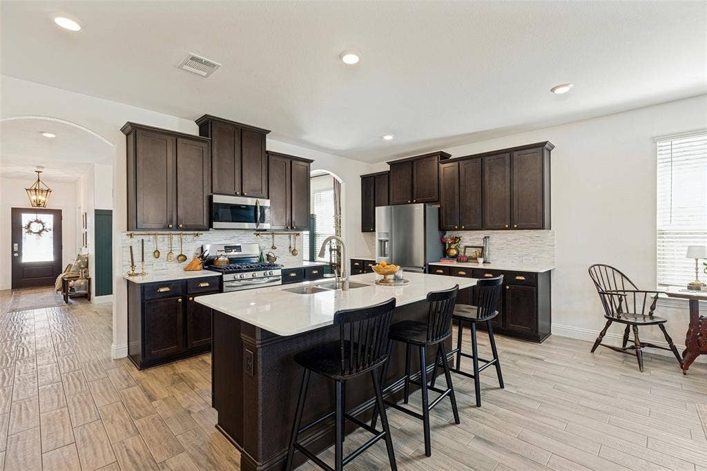 Kitchen featuring dark wood cabinetry, white stone countertops, and stainless steel appliances