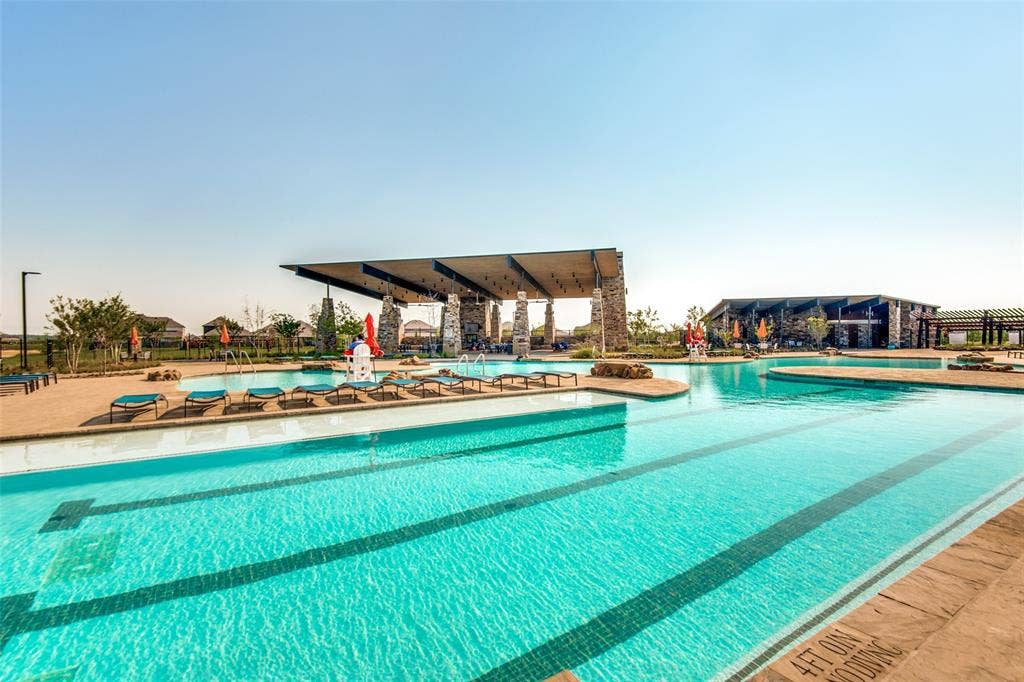 Expansive swimming pool with integrated lap lanes, surrounded by a stone-clad shaded pavilion and concrete decking