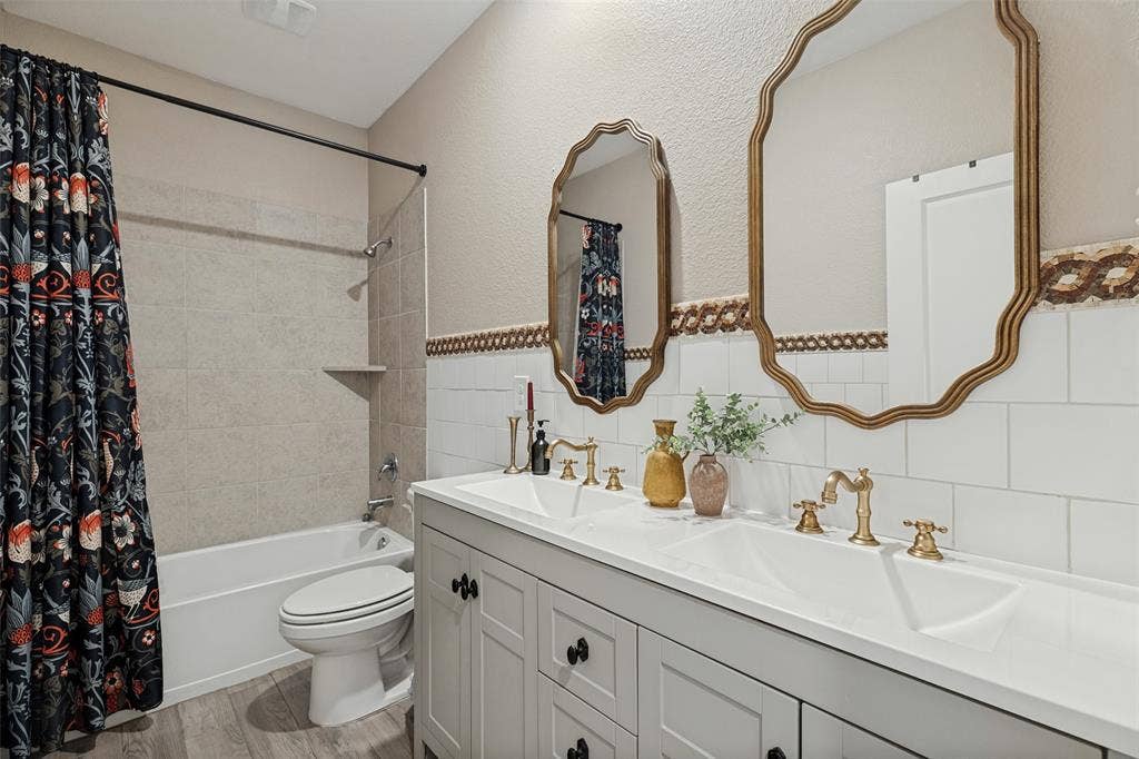 Double vanity with integrated sinks, brushed gold fixtures, and ornate framed mirrors