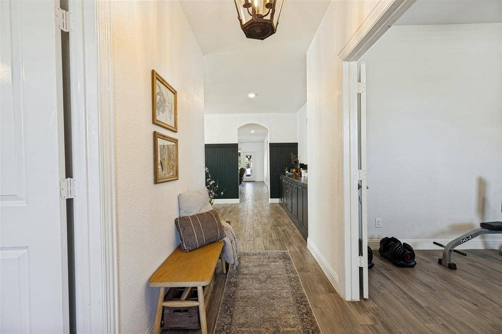 Hallway with wood-finish flooring, white walls, and a decorative overhead light fixture