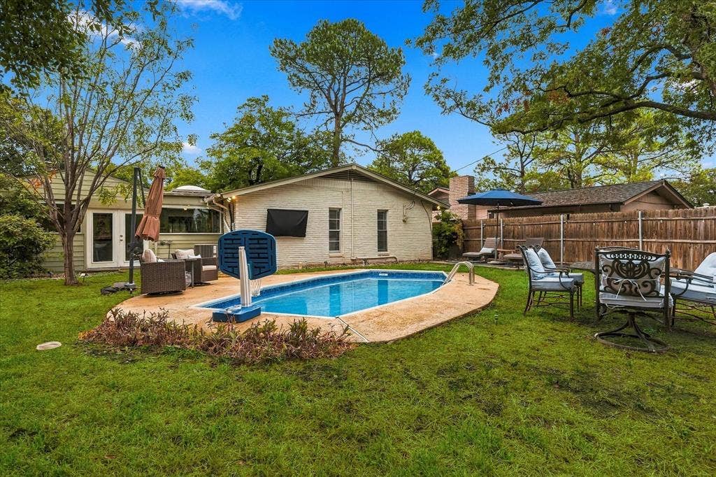 306 W Northgate Drive, Irving, TX 75062 Expansive backyard featuring a built-in swimming pool with concrete coping, a wooden privacy fence, and mature trees