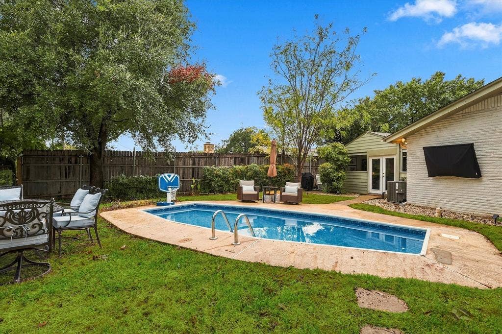 306 W Northgate Drive, Irving, TX 75062 Rectangular swimming pool with concrete decking, surrounded by a manicured lawn and mature trees