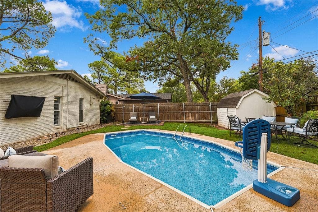 306 W Northgate Drive, Irving, TX 75062 Expansive backyard featuring a swimming pool, a storage shed, a wood fence, and mature trees
