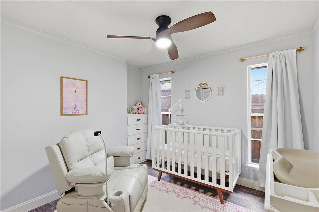 306 W Northgate Drive, Irving, TX 75062 Crown molding, ceiling fan, and two windows with white curtains