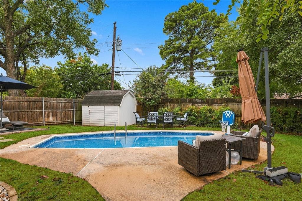 306 W Northgate Drive, Irving, TX 75062 In-ground swimming pool with surrounding concrete patio, bordered by a wood privacy fence