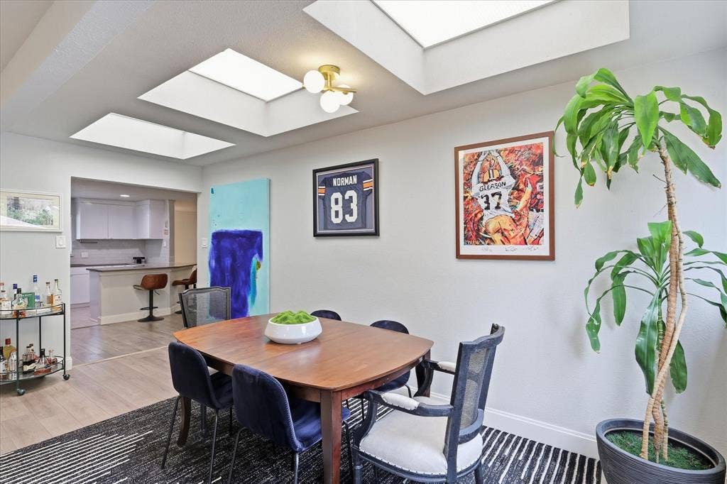 306 W Northgate Drive, Irving, TX 75062 Dining area with multiple skylights, overhead lighting fixture, and light wood-finish flooring