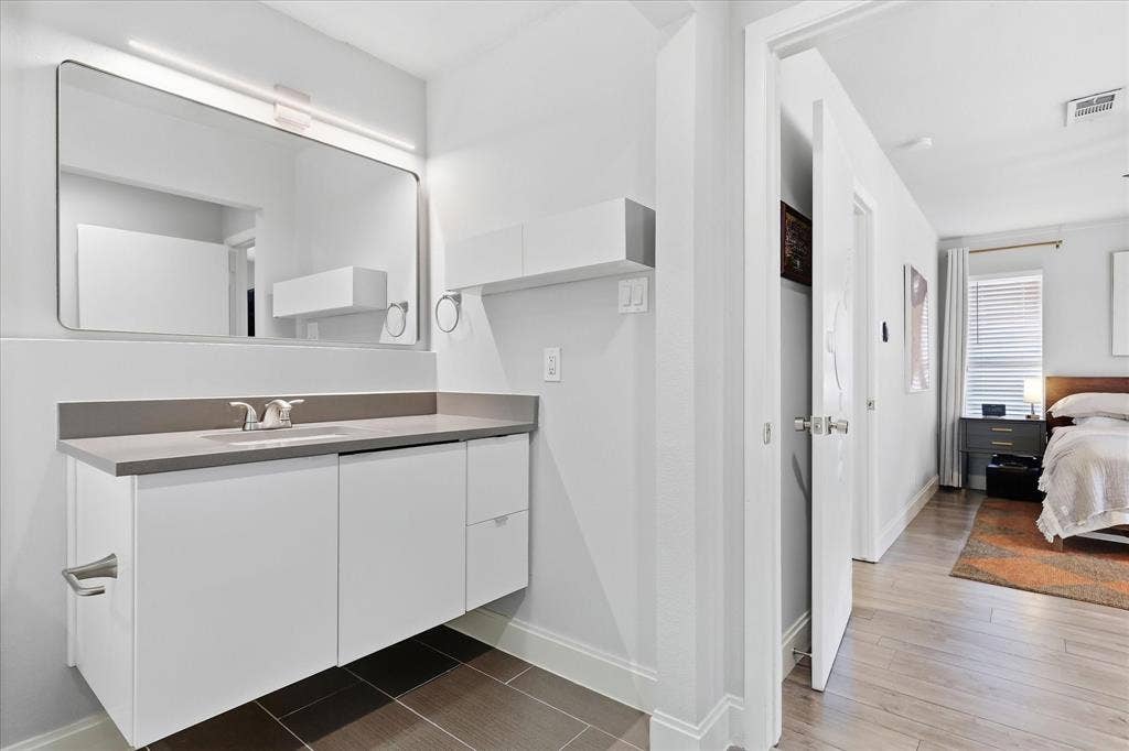 306 W Northgate Drive, Irving, TX 75062 Primary Floating vanity with a light gray quartz countertop, rectangular undermount sink, and polished chrome faucet