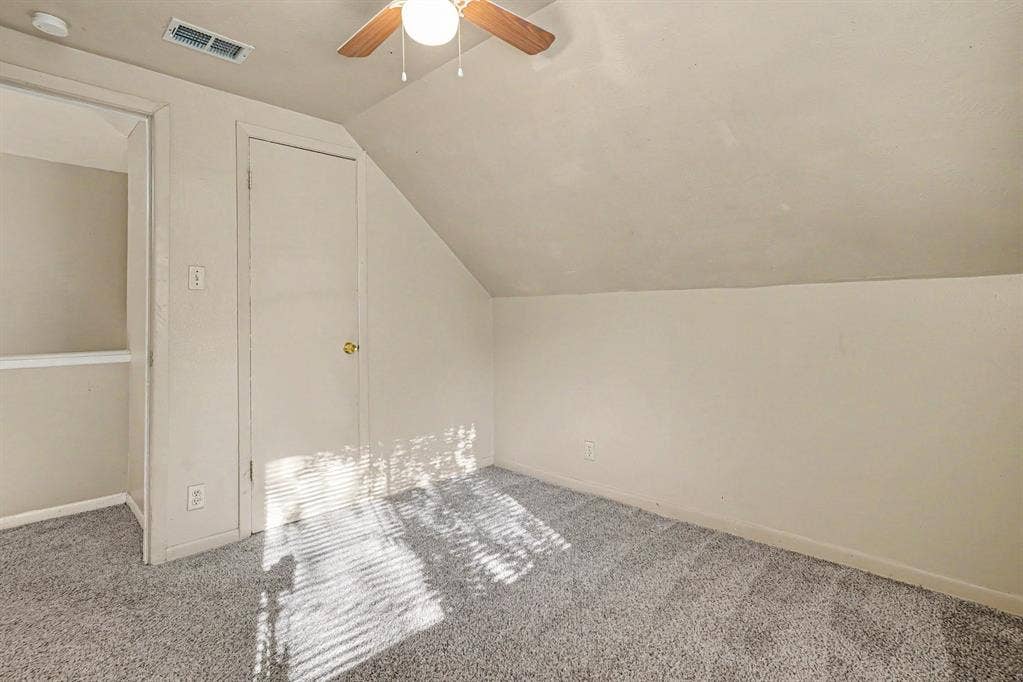 1414 Finley Road, Irving, TX 75062 Sloped ceiling room featuring a ceiling fan with light, gray carpeting, and a closet with a gold-tone doorknob