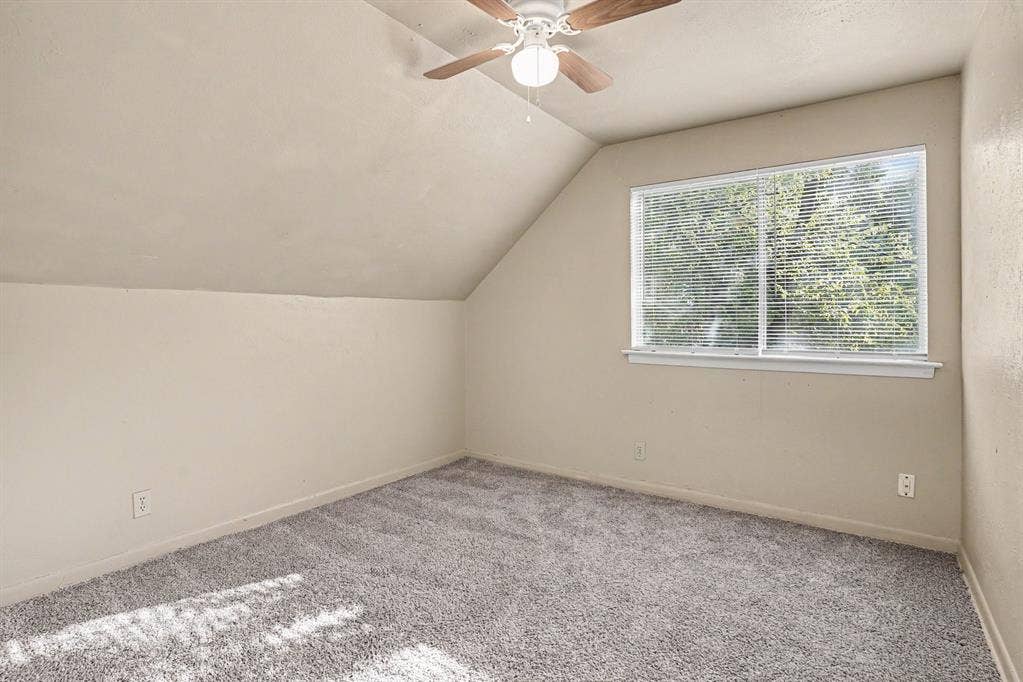 1414 Finley Road, Irving, TX 75062 Sloped ceiling room featuring a ceiling fan, recessed window with blinds, and gray carpeting