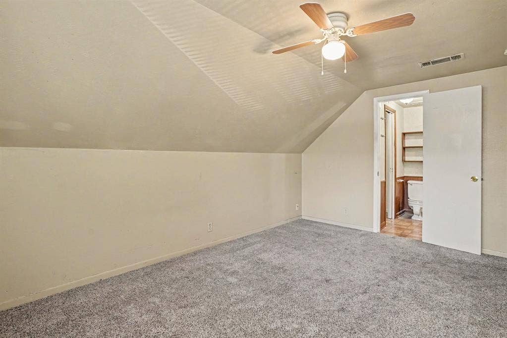 1414 Finley Road, Irving, TX 75062 Sloped ceilings with a ceiling fan light fixture, carpeted flooring, and an adjoining room with built-in shelving
