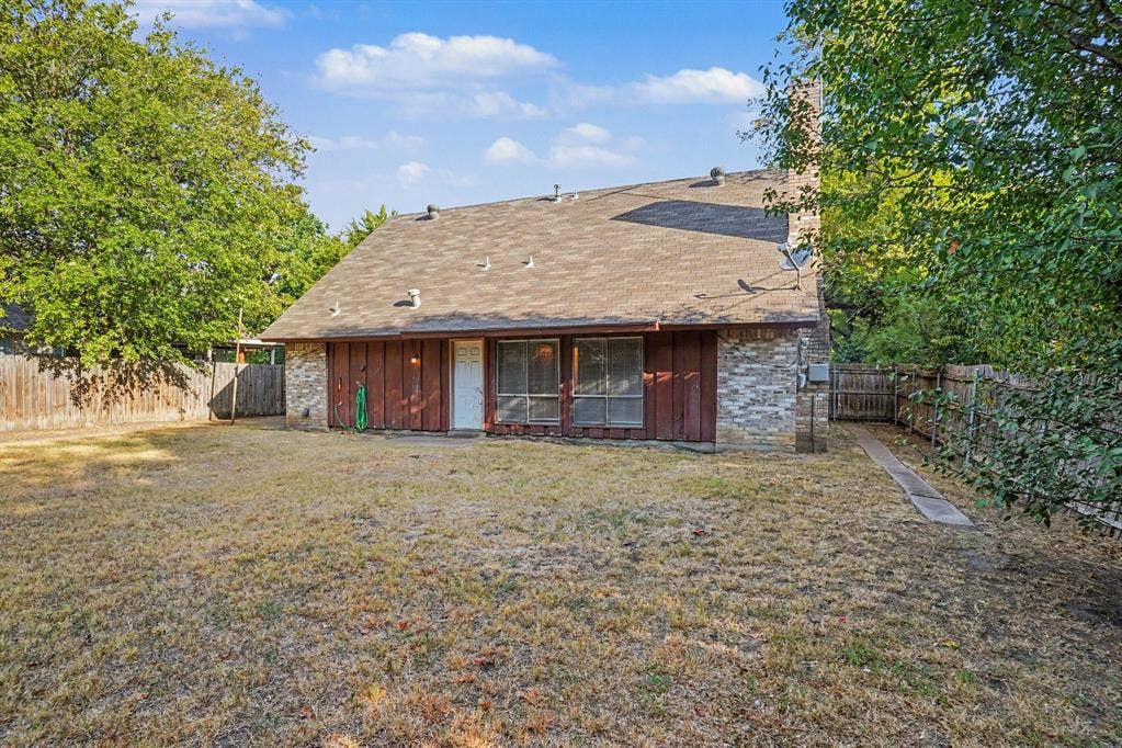 1414 Finley Road, Irving, TX 75062 Rear exterior with brick and wood siding, a chimney, and a fenced perimeter