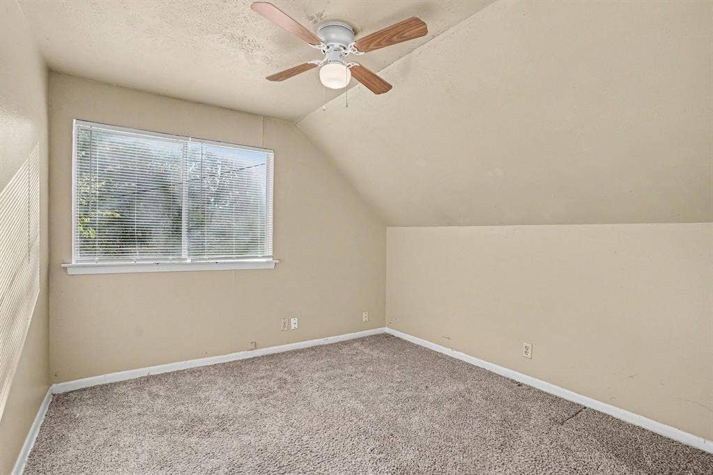 1414 Finley Road, Irving, TX 75062 Room featuring sloped ceilings, carpet flooring, a window with blinds, and a ceiling fan with light fixture