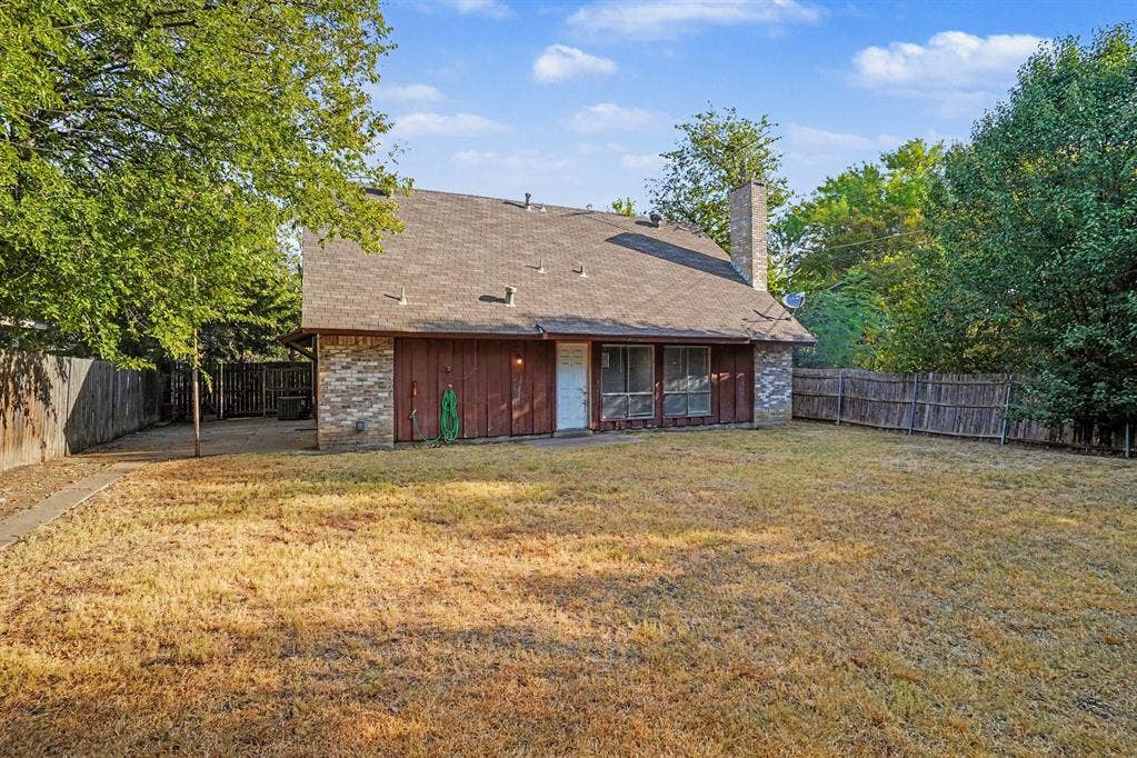 1414 Finley Road, Irving, TX 75062 Expansive backyard featuring a partial brick and wood exterior, multiple mature trees, and a privacy fence