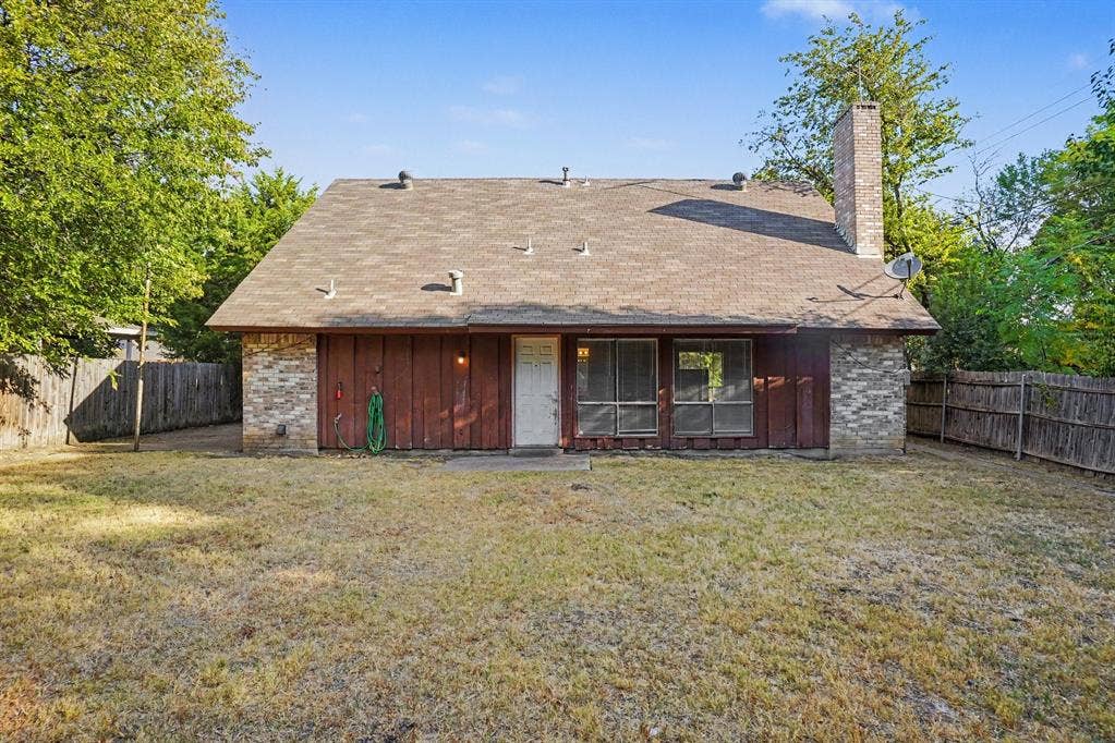 1414 Finley Road, Irving, TX 75062 Expansive backyard featuring a wood fence, mature trees, and a brick chimney