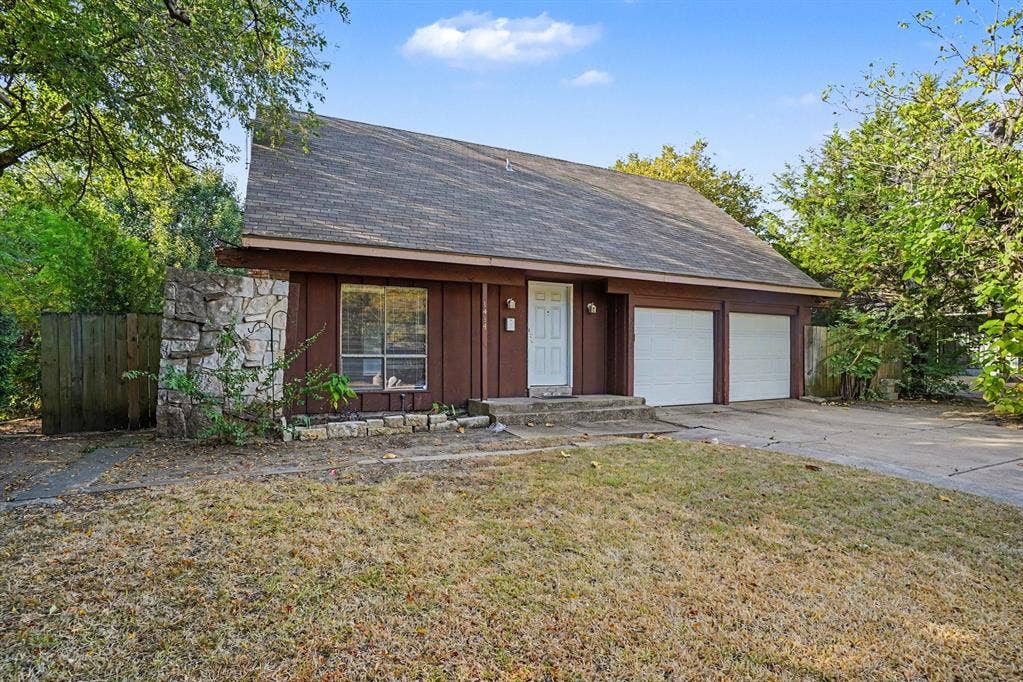 1414 Finley Road, Irving, TX 75062 Wood siding exterior with stone accents, featuring a two-car garage, front entry door, and asphalt shingle roof
