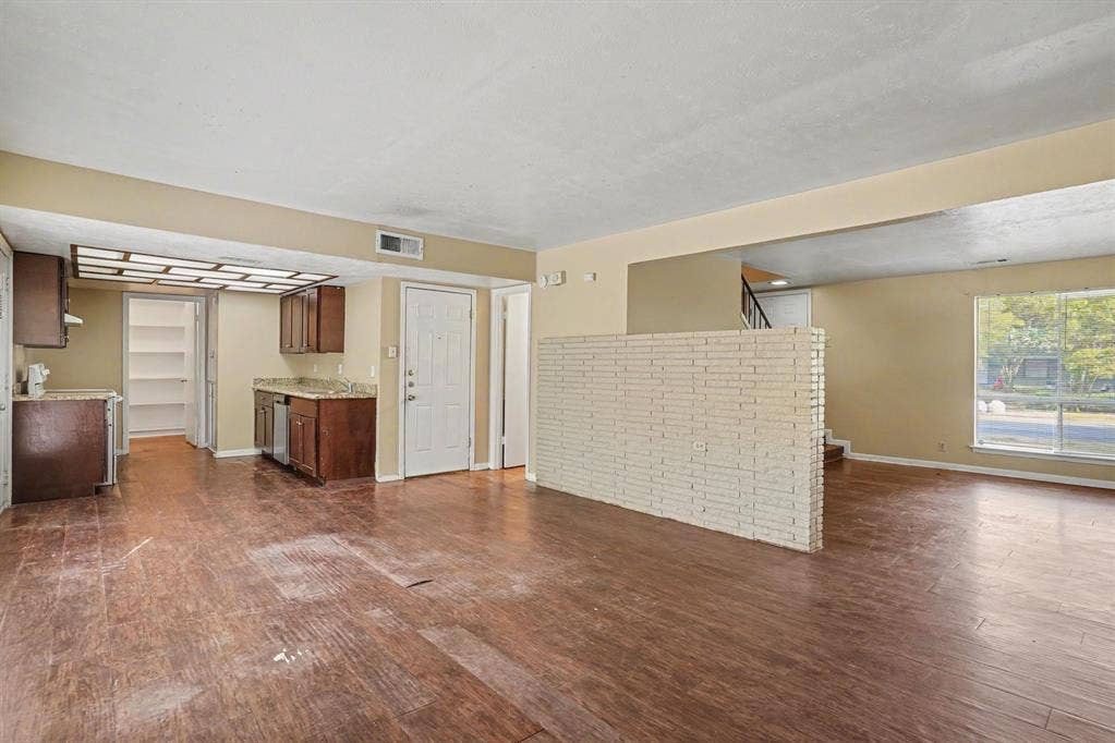 1414 Finley Road, Irving, TX 75062 Wood-finish flooring throughout, with a kitchen area featuring wood cabinetry, a built-in dishwasher, and granite-style countertops