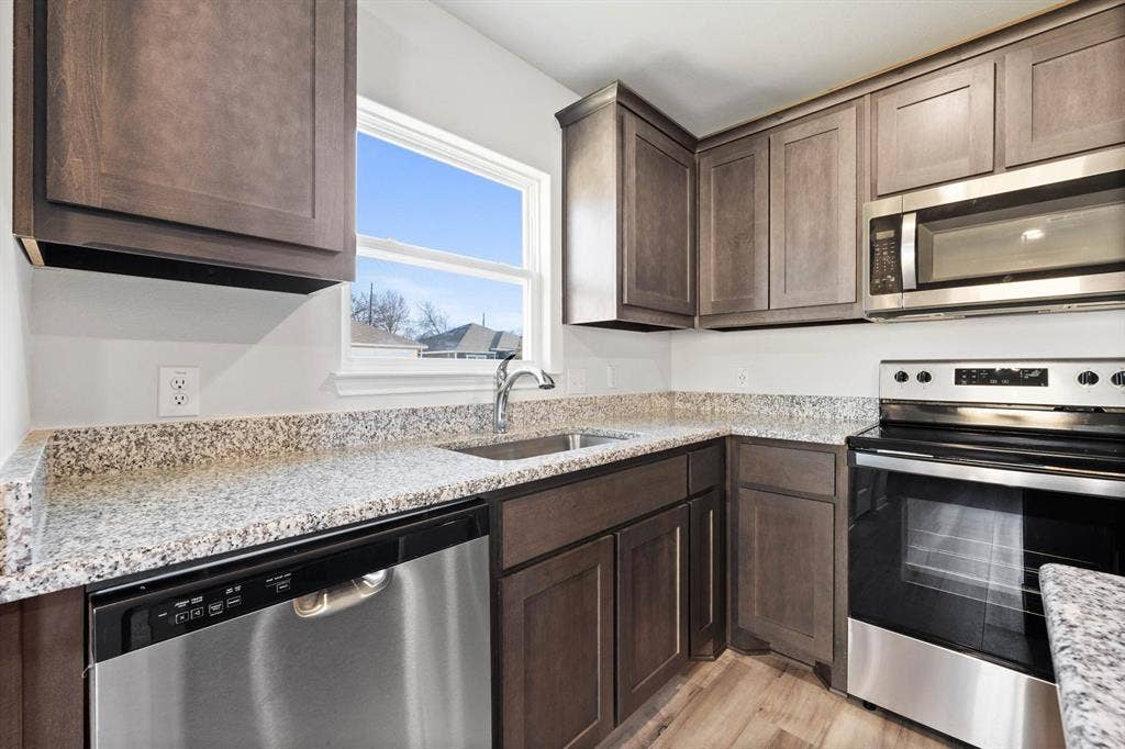 6308 Hyena Hollow Drive, Dallas, TX 75241 Kitchen with dark brown cabinetry, light stone countertops, sink, light hardwood / wood-style floors, and appliances with stainless steel finishes