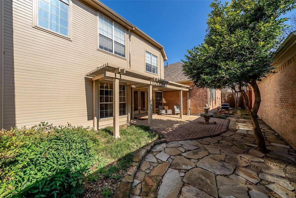 8640 Breakers Point, Dallas, TX 75243 Outdoor living space featuring a pergola-covered patio, brick paver surface, flagstone pathway, and mature landscaping